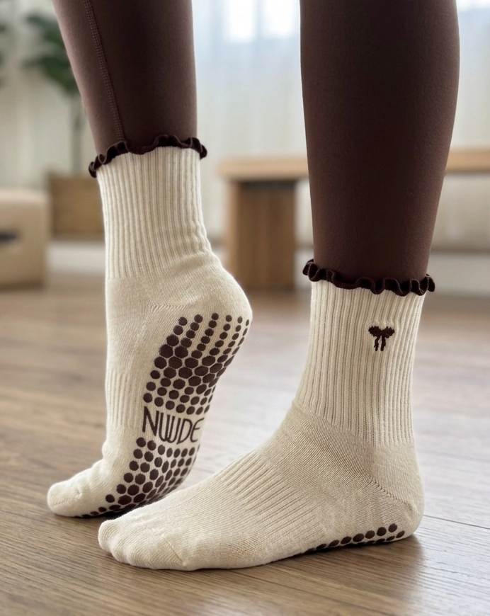 Nuude Pilates grip socks worn during studio workout, cream socks with brown grip sole