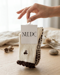Pilates grip socks by Nuude in cream and brown with anti-slip sole, shown in minimal packaging